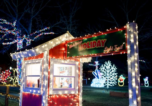 The image shows a holiday light trail with festive decorations, including a booth and illuminated figures and trees, all lit up at night.
