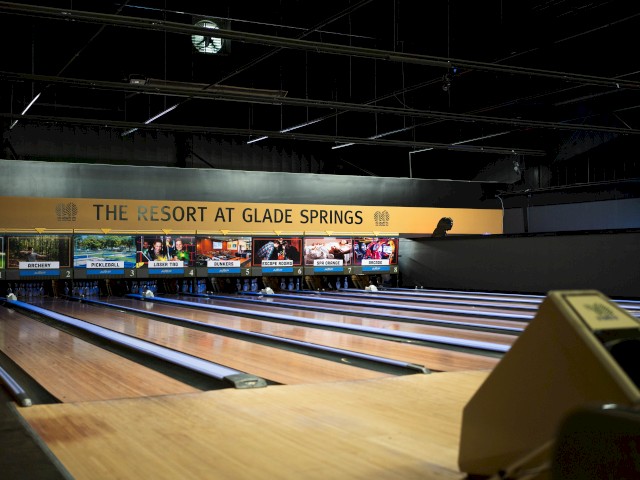 A bowling alley with multiple lanes and screens, featuring signage for 