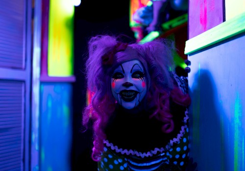 A creepy clown with vivid face paint and colorful hair lurks in a dimly lit, neon-colored hallway, creating an eerie atmosphere.