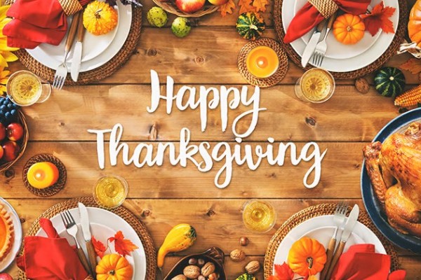 A festive Thanksgiving table with a turkey, pumpkins, sunflowers, and fall decor surrounding a 