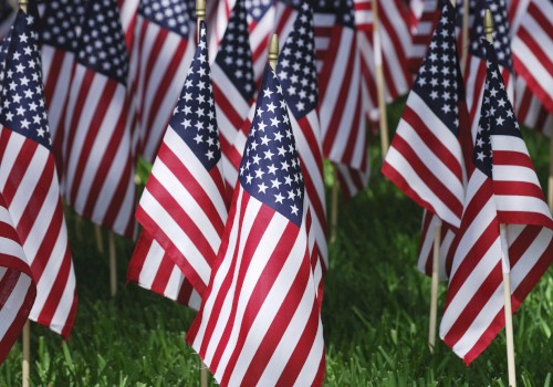 Multiple small American flags are displayed on sticks, planted in the grass, creating a patriotic display.