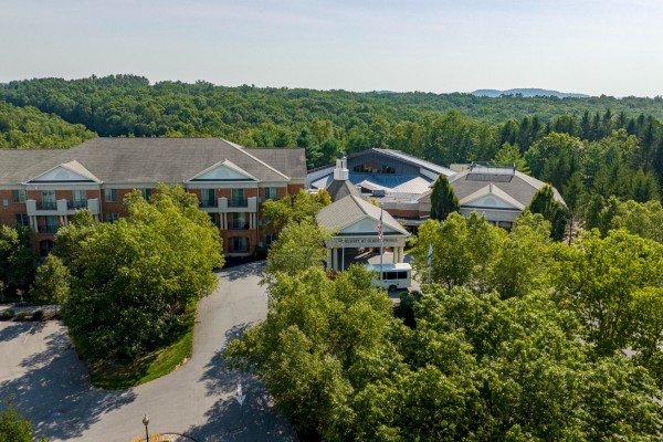An aerial view of a resort surrounded by trees, with parking lots, a bus, and buildings labeled 