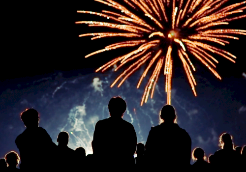 People watch fireworks explode in the night sky during a celebration or event.