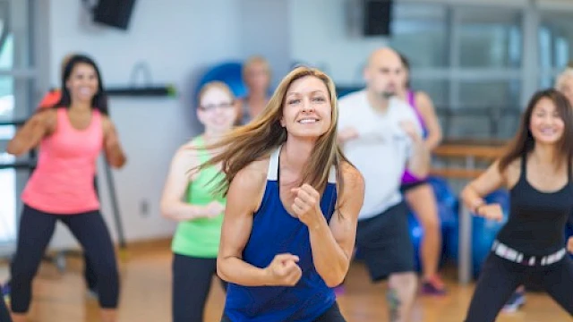 People participating in a lively, energetic dance or fitness class in a bright, modern studio space.