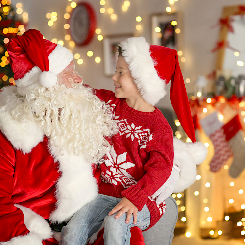 A child and Santa Claus share a joyful moment with Christmas decorations in the background.